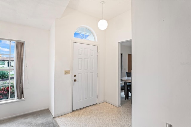 carpeted foyer with lofted ceiling