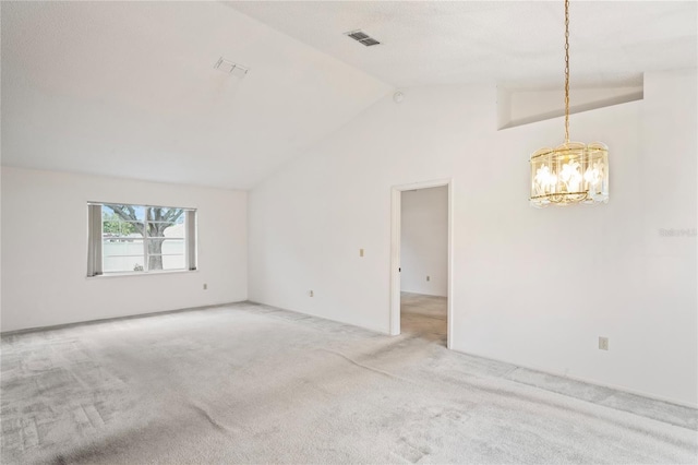 carpeted empty room featuring an inviting chandelier and vaulted ceiling