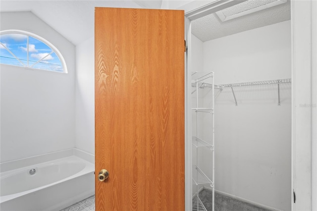 bathroom featuring lofted ceiling, a washtub, and a textured ceiling