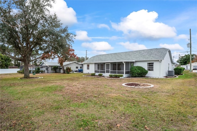 view of front of house featuring a front yard, central air condition unit, and a sunroom