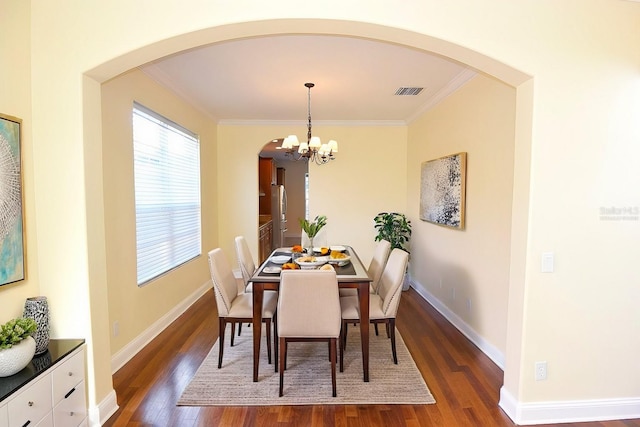 dining space featuring ornamental molding, dark wood-type flooring, and an inviting chandelier