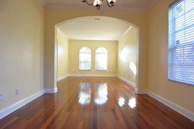 empty room with dark hardwood / wood-style flooring, a chandelier, and crown molding