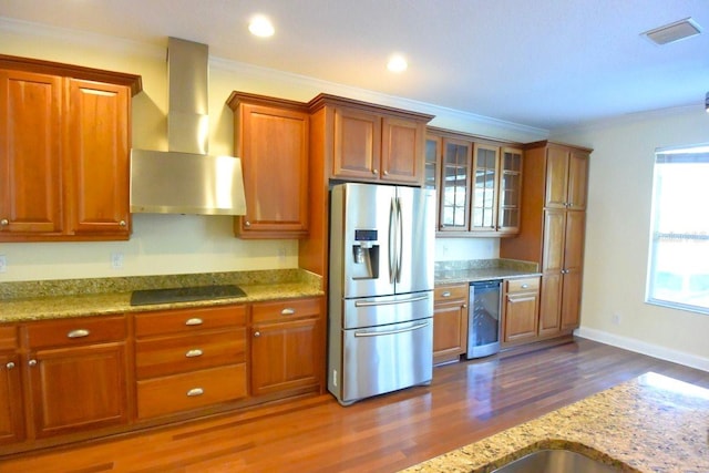 kitchen with ornamental molding, stainless steel fridge, wall chimney exhaust hood, and dark hardwood / wood-style floors