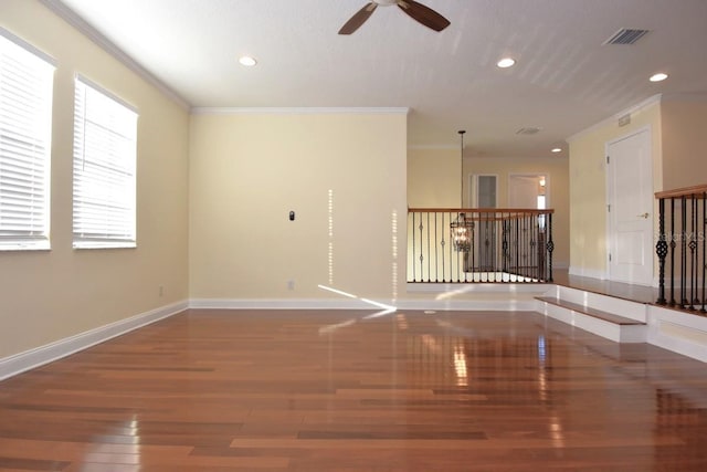 empty room with wood-type flooring, ceiling fan, crown molding, and a wealth of natural light