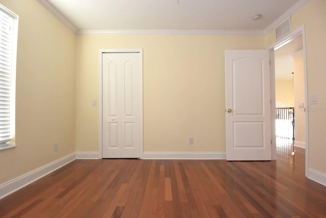 unfurnished bedroom with a closet, crown molding, and dark hardwood / wood-style flooring