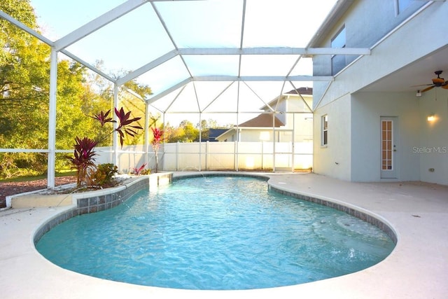 view of pool with ceiling fan, glass enclosure, and a patio area