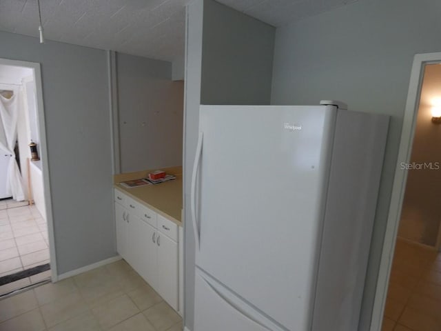 kitchen with white cabinets, white fridge, and light tile patterned flooring