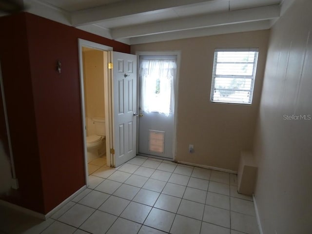 interior space with beam ceiling, ensuite bathroom, and light tile patterned flooring