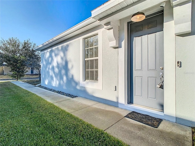 view of exterior entry featuring a lawn