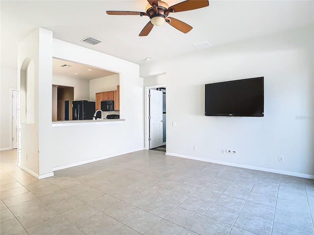 unfurnished living room with light tile patterned flooring, ceiling fan, and sink