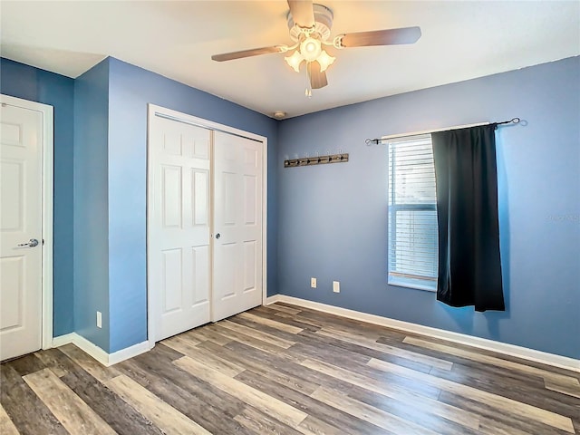 unfurnished bedroom with ceiling fan, dark hardwood / wood-style flooring, and a closet