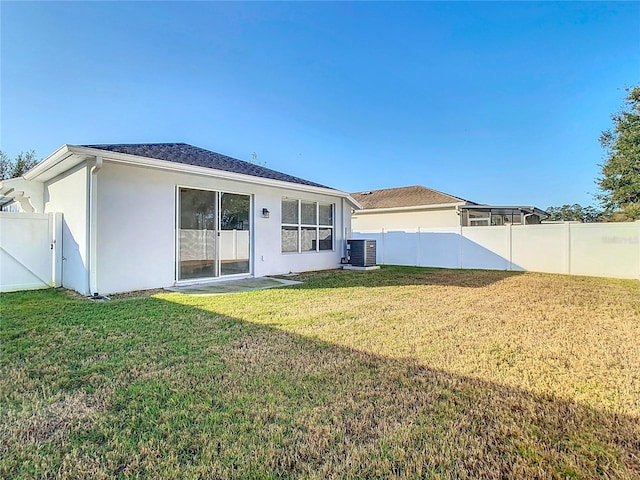 rear view of property with central AC and a lawn