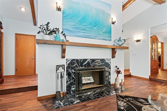 living room featuring wood-type flooring, lofted ceiling with beams, and a premium fireplace