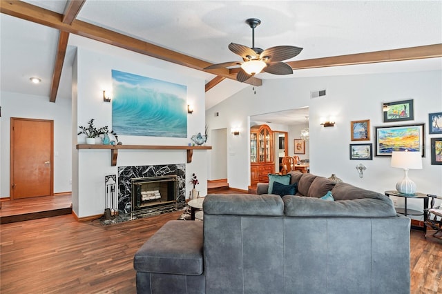 living room with ceiling fan, dark hardwood / wood-style flooring, lofted ceiling with beams, and a fireplace