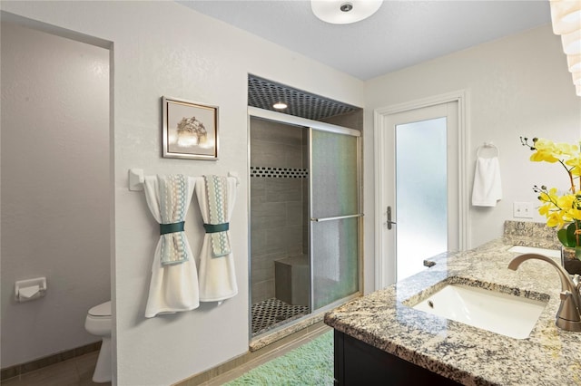 bathroom featuring tile patterned floors, toilet, a shower with door, and vanity