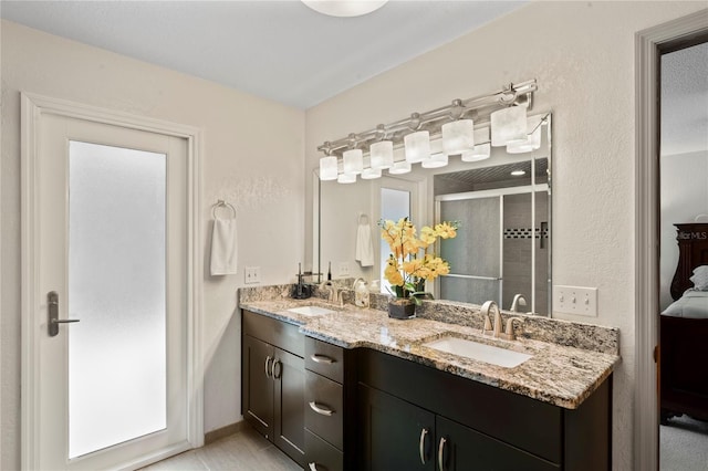 bathroom featuring a shower with shower door, vanity, and tile patterned floors