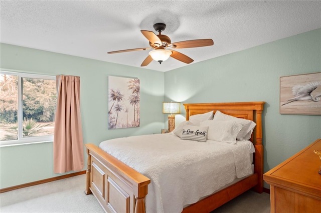 carpeted bedroom featuring ceiling fan and a textured ceiling