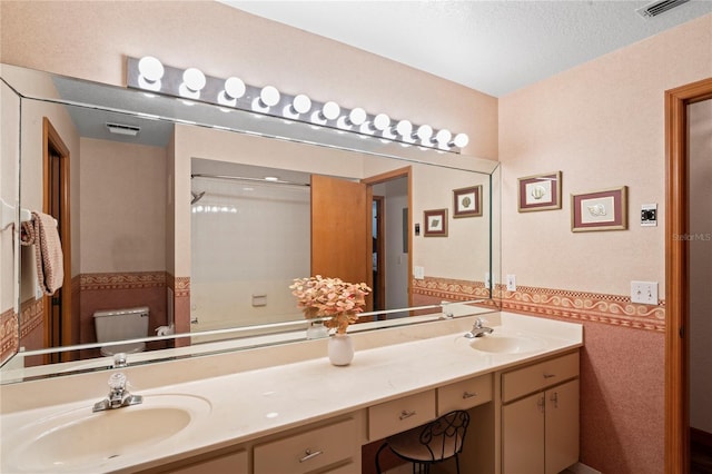 bathroom featuring a textured ceiling, toilet, and vanity