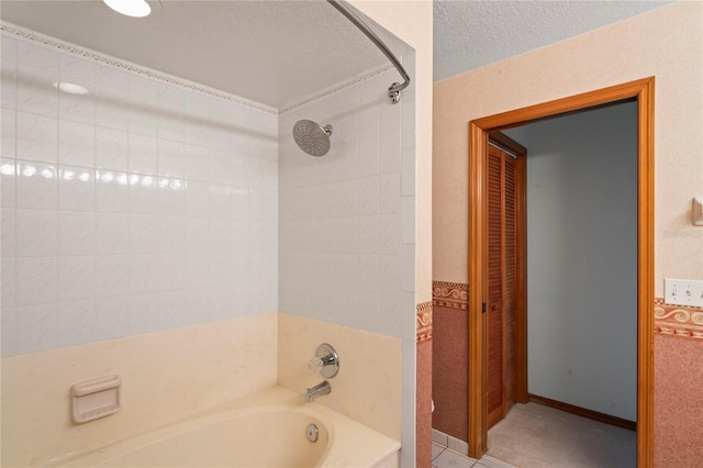 bathroom with a textured ceiling, tile patterned floors, tile walls, and bathing tub / shower combination