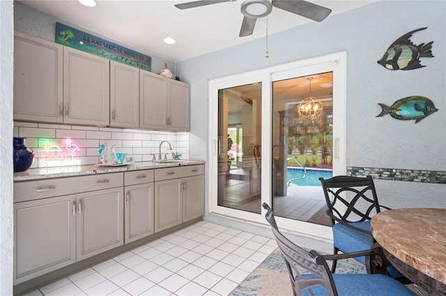 kitchen featuring gray cabinets, ceiling fan, decorative backsplash, and sink