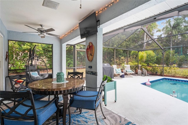 view of swimming pool featuring ceiling fan, glass enclosure, and a patio