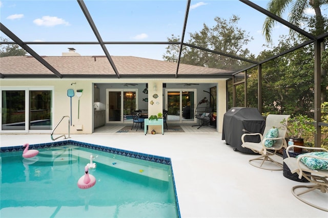 rear view of property with ceiling fan, glass enclosure, and a patio