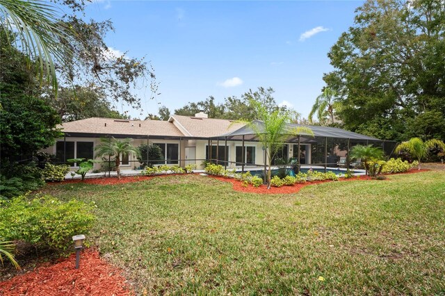 rear view of property with a lawn, a pool, and glass enclosure