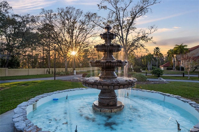 pool at dusk featuring a lawn