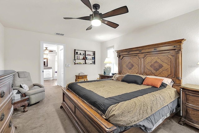 bedroom featuring light carpet, visible vents, ensuite bath, and ceiling fan