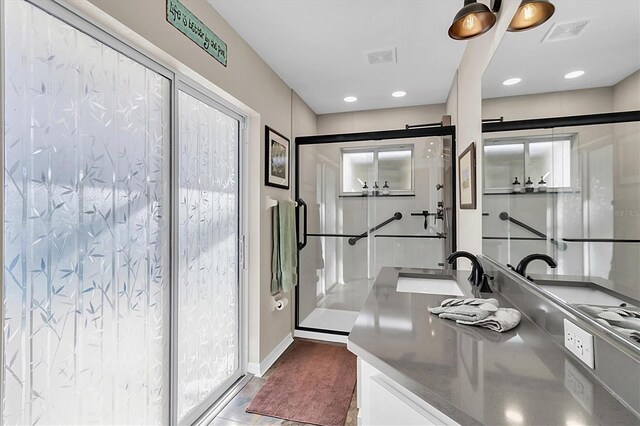 full bath featuring vanity, a shower stall, baseboards, and visible vents