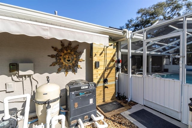 view of side of home featuring glass enclosure and an outdoor pool