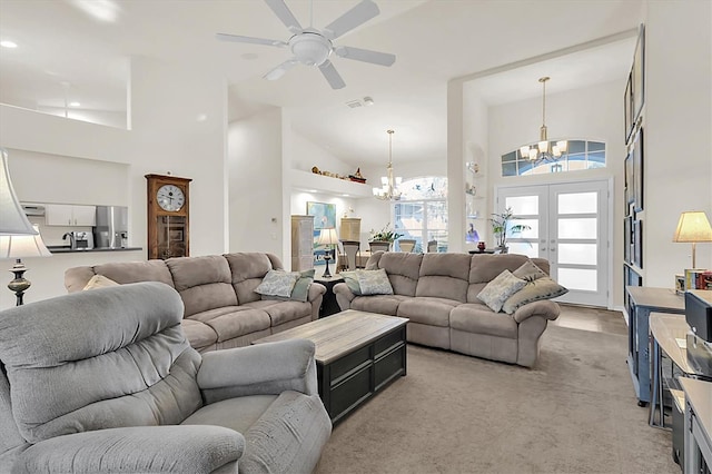 living room with visible vents, light carpet, ceiling fan with notable chandelier, french doors, and a towering ceiling