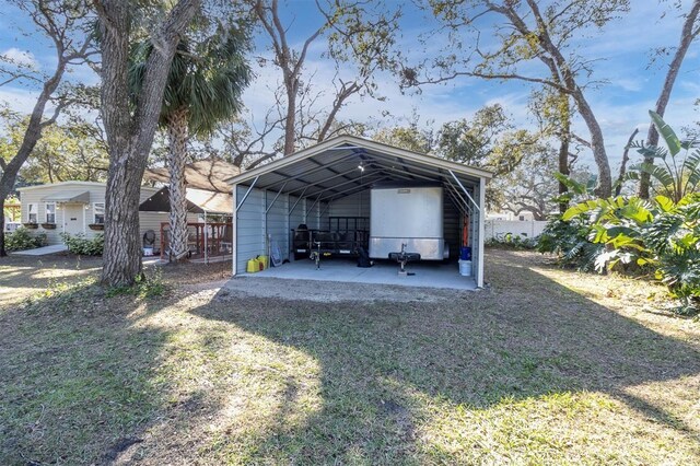 exterior space with a detached carport, fence, and dirt driveway