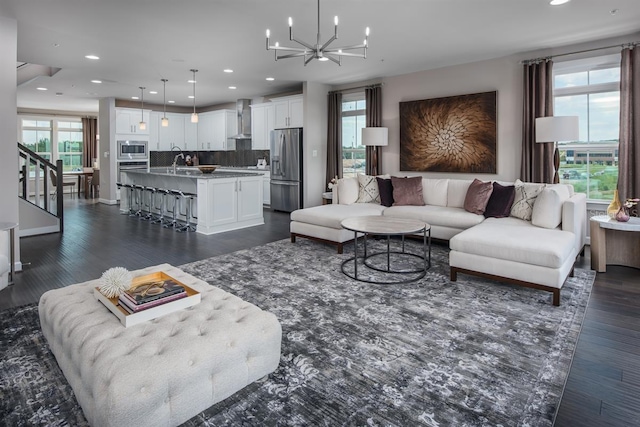 living room featuring sink, plenty of natural light, a notable chandelier, and dark wood-type flooring