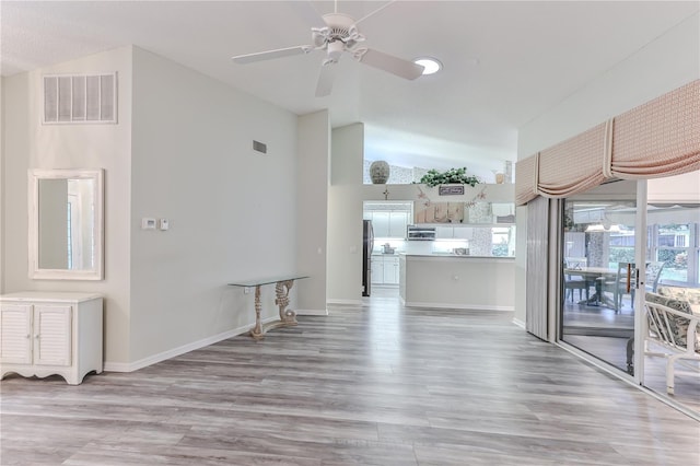 unfurnished living room with light wood-type flooring, ceiling fan, and high vaulted ceiling