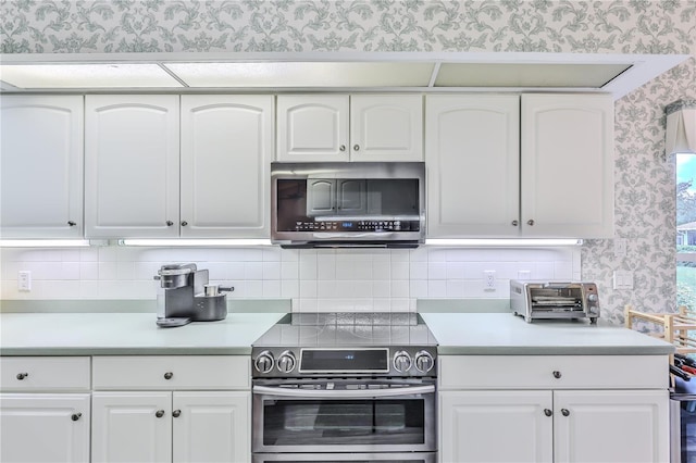 kitchen with stainless steel appliances, white cabinetry, and tasteful backsplash