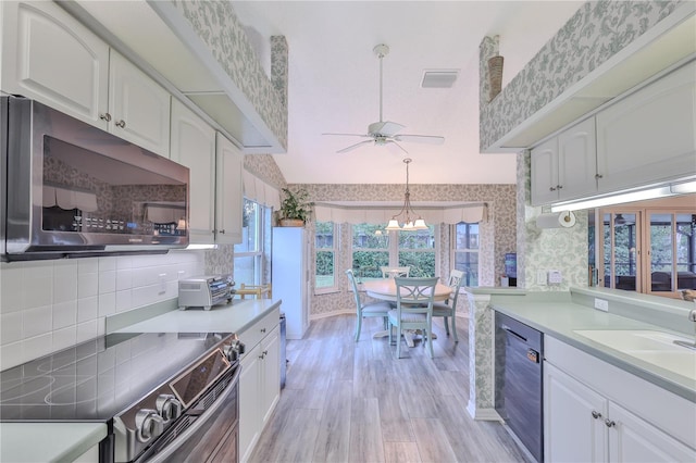 kitchen featuring appliances with stainless steel finishes, ceiling fan with notable chandelier, white cabinetry, and light hardwood / wood-style floors