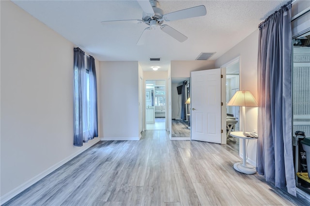 empty room featuring a textured ceiling, ceiling fan, and light hardwood / wood-style floors