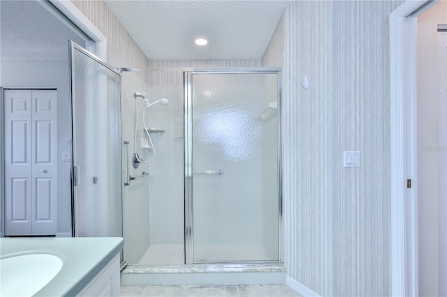 bathroom with an enclosed shower, vanity, and a textured ceiling