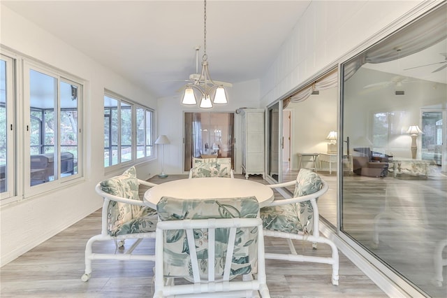 sunroom featuring ceiling fan with notable chandelier