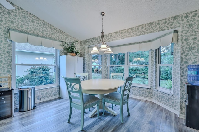 dining room featuring hardwood / wood-style flooring, a textured ceiling, and lofted ceiling