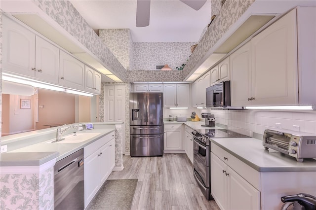 kitchen featuring white cabinetry, stainless steel appliances, light hardwood / wood-style floors, sink, and backsplash