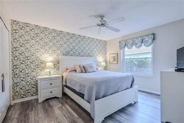 bedroom with ceiling fan, a textured ceiling, dark hardwood / wood-style flooring, and a closet