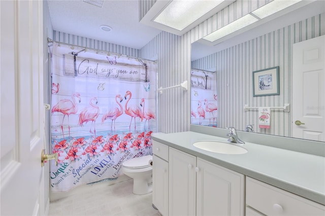 bathroom with toilet, vanity, and a textured ceiling