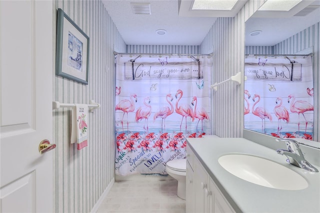 bathroom featuring toilet, vanity, a shower with curtain, and a textured ceiling