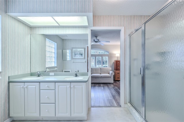 bathroom featuring a textured ceiling, ceiling fan, a shower with door, and vanity