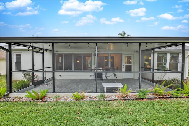 rear view of property featuring a patio area, a lanai, a yard, and a sunroom