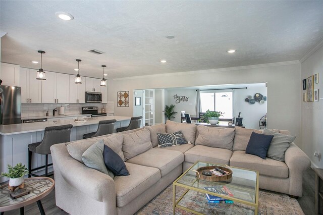 living room featuring ornamental molding, light hardwood / wood-style flooring, and sink