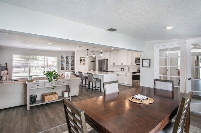 dining room with a textured ceiling and dark hardwood / wood-style flooring