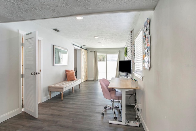 office with a textured ceiling, a barn door, and dark hardwood / wood-style floors